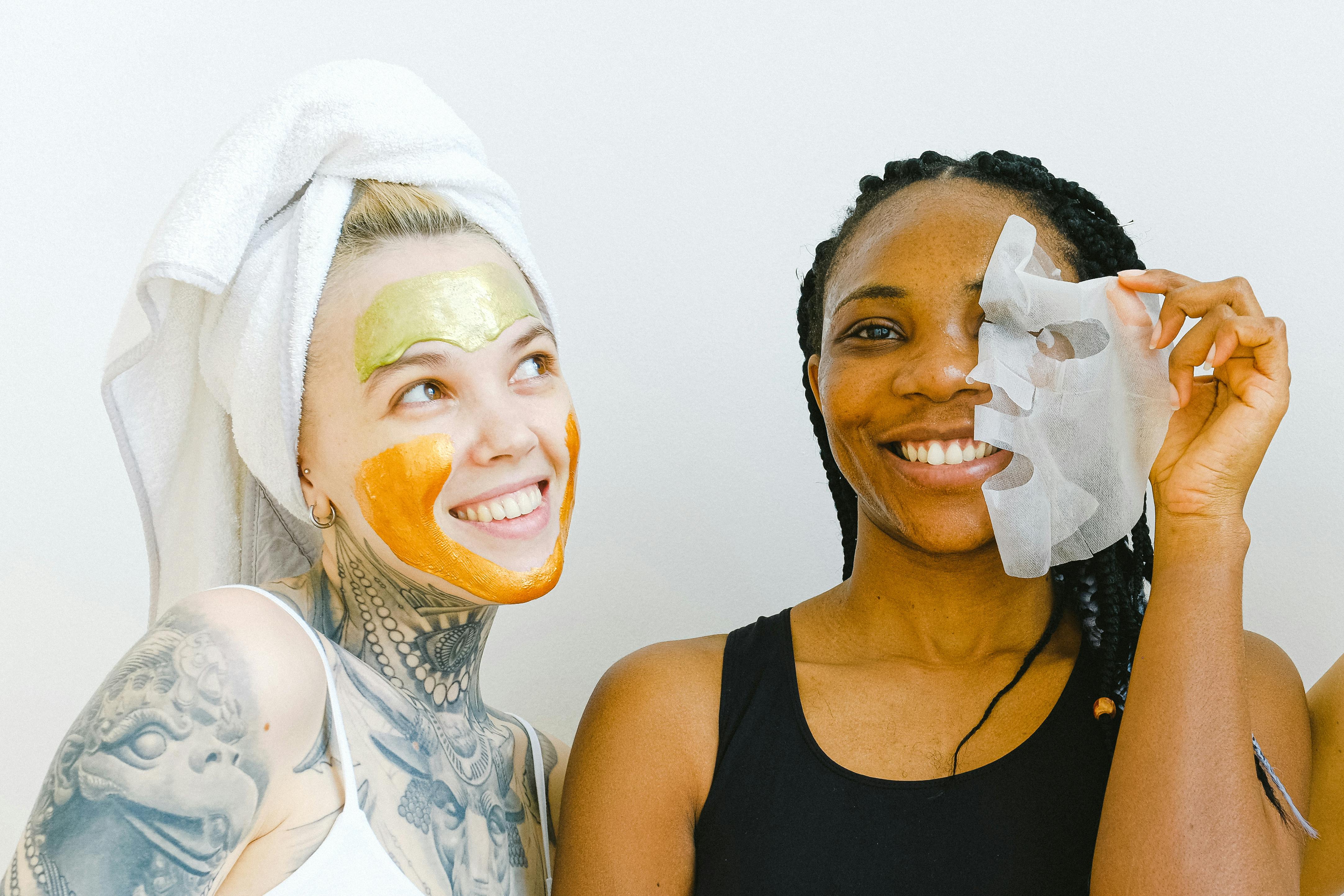 Two women smiling with face masks applied during a skincare routine